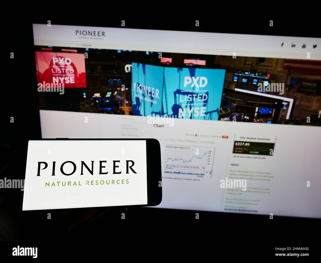Persona che tiene il telefono cellulare con il logo del business US Pioneer Natural Resources Company sullo schermo di fronte alla pagina web. Mettere a fuoco sul display del telefono. Foto Stock