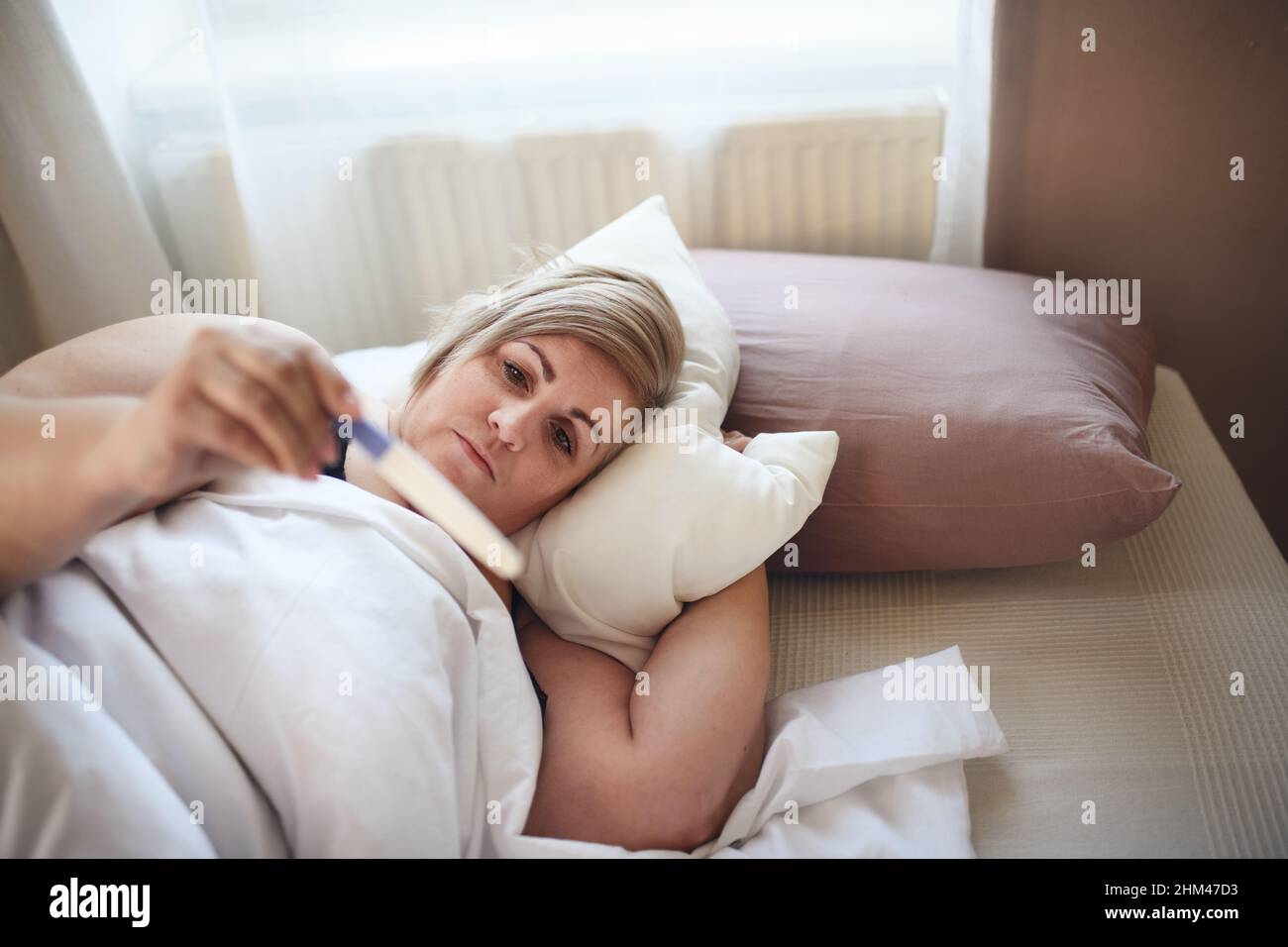 Donna malata sovrappeso che si trova a letto a casa. Foto Stock