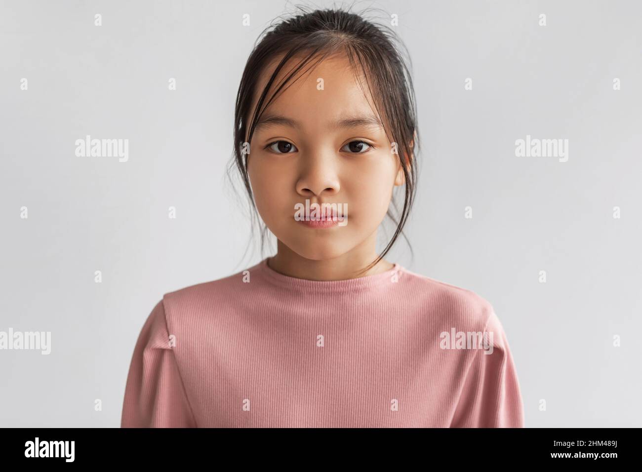 Ritratto di ragazza asiatica seria guardando la macchina fotografica, sfondo grigio Foto Stock