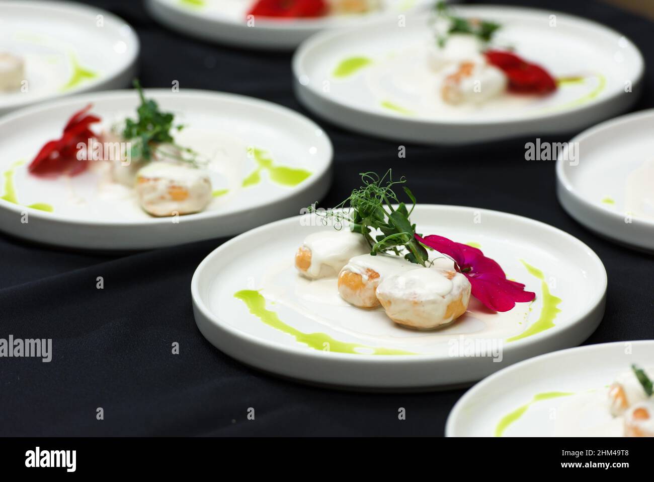 lo chef prepara un piatto di palle di pesce in una salsa cremosa Foto Stock