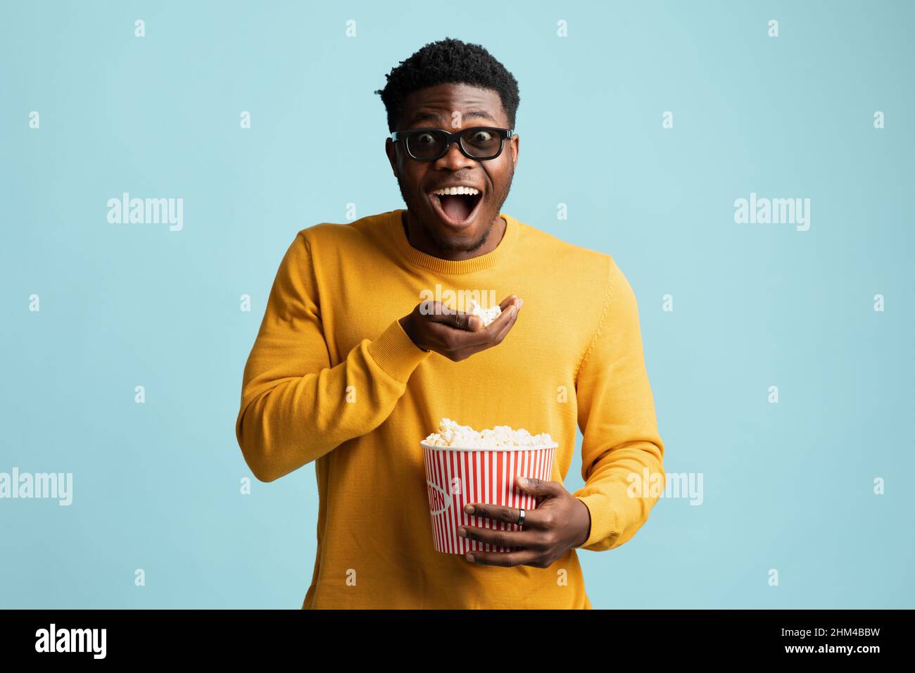 Ragazzo nero eccitato che mangia popcorn e sorride, usando 3D bicchieri Foto Stock