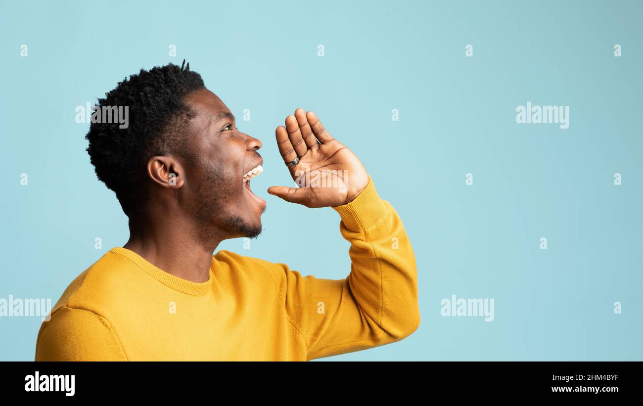 Felice ragazzo nero che dice qualcosa fuori forte, spazio di copia Foto Stock
