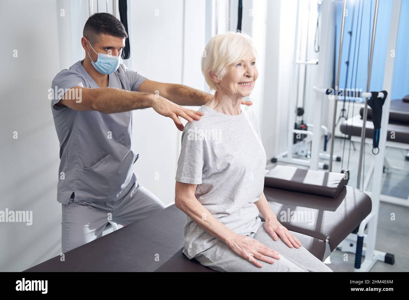 Fisioterapista che dà il massaggio alle spalle della signora felice Foto Stock