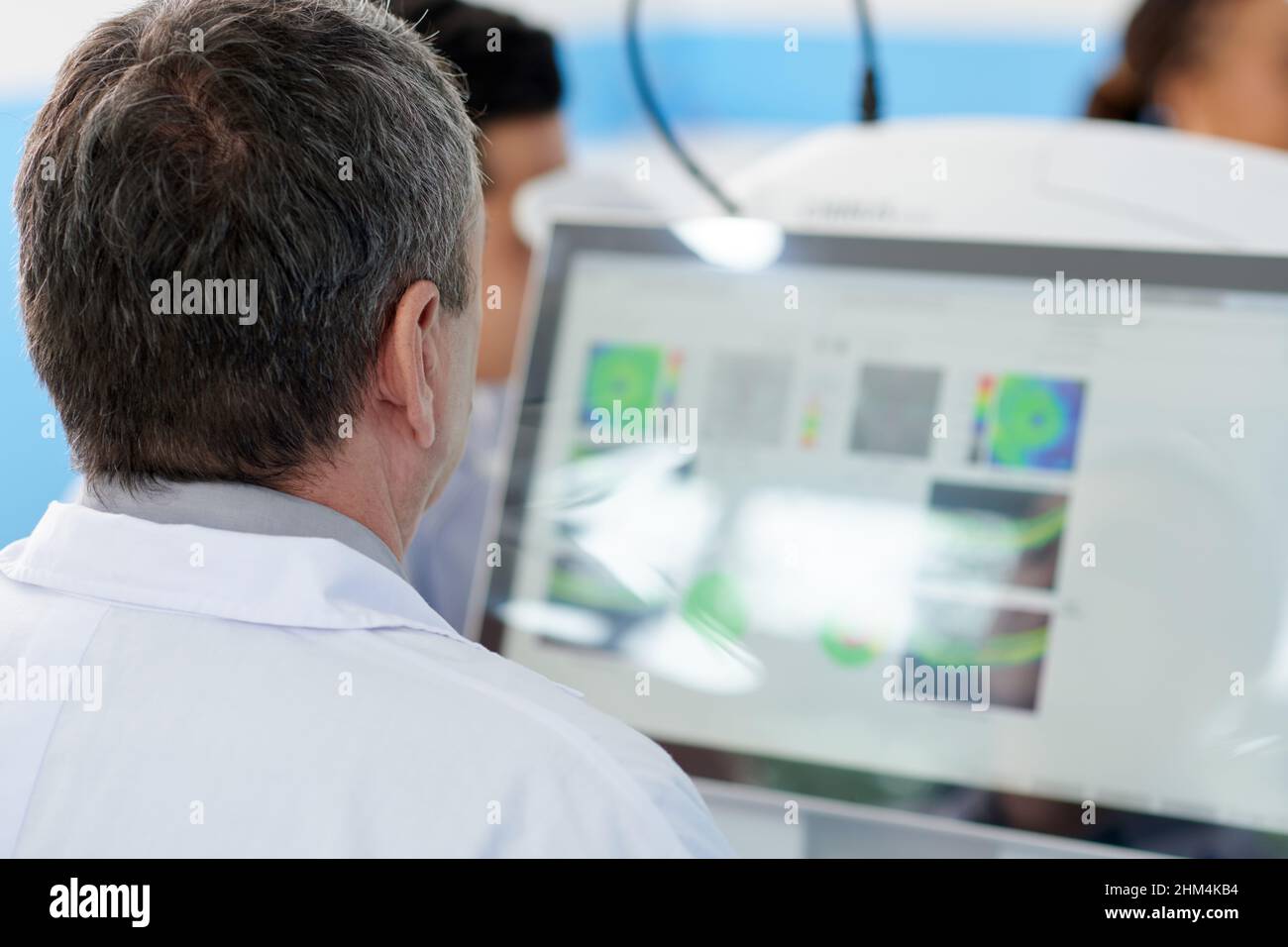 Optometristo che utilizza apparecchiature moderne per diagnosticare e identificare i principali problemi visivi della paziente femminile Foto Stock