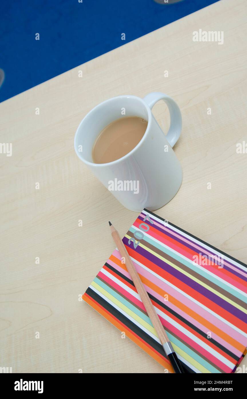 Vista ad angolo alto di Una matita su un diario con una tazza di tè, credito: Fotografia creativa / Stuart Cox / Avalon Foto Stock