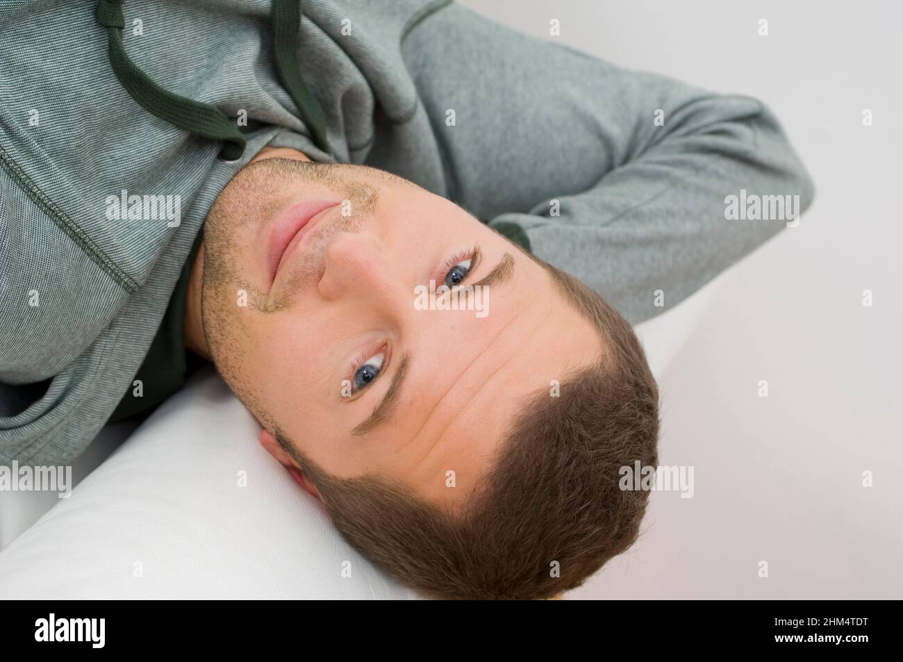 Ritratto di un giovane uomo che posa sul letto e sorridente, Credit:Photoshot Creative / Stuart Cox / Avalon Foto Stock