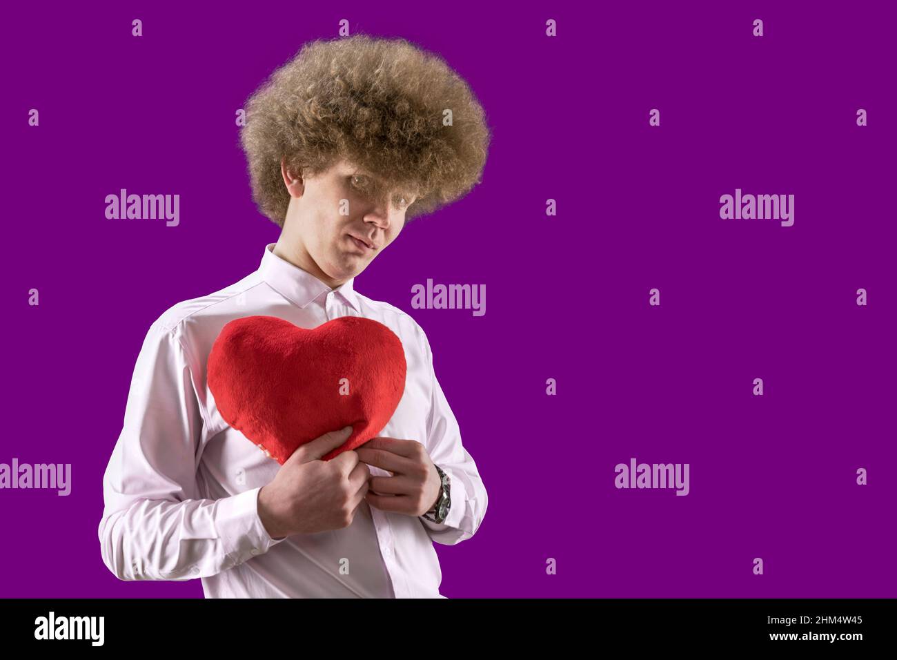 San Valentino. Amante. Un uomo con capelli ricci tiene un giocattolo morbido a forma di cuore nelle sue mani. Un regalo per il vostro compagno di anima. Amore. Il 14th febbraio Foto Stock