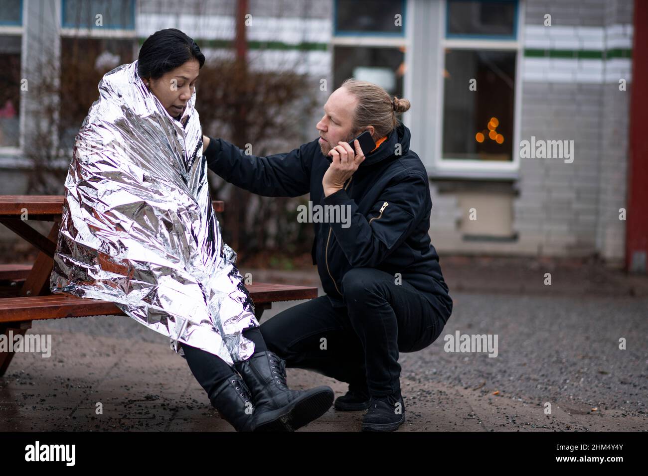 Uomo che chiede l'ambulanza per la donna in coperta di emergenza Foto Stock