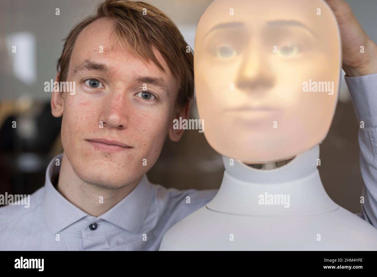 Ritratto del giovane con assistente vocale robot Foto Stock