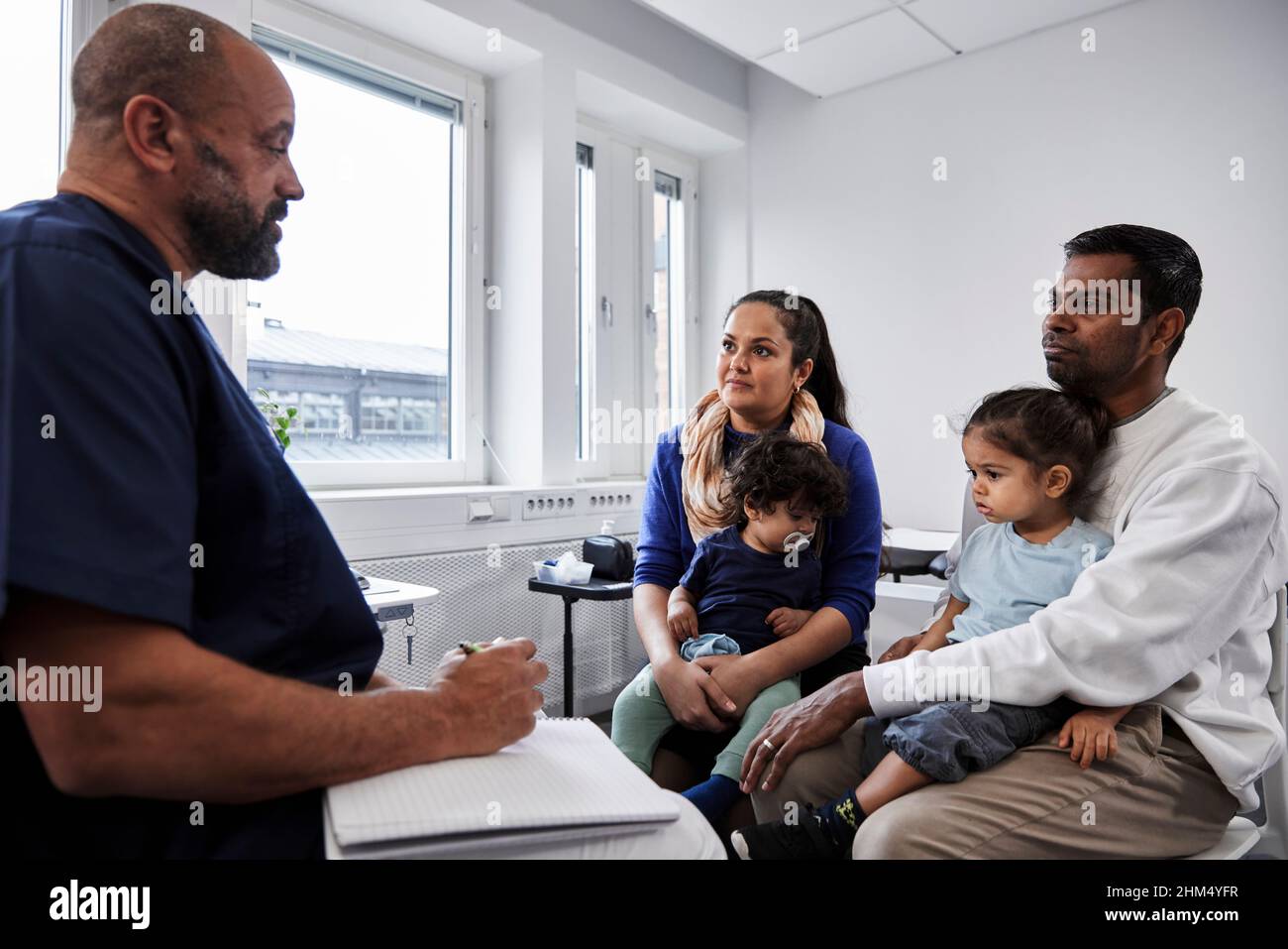 Medico di sesso maschile che parla con la famiglia con i bambini Foto Stock