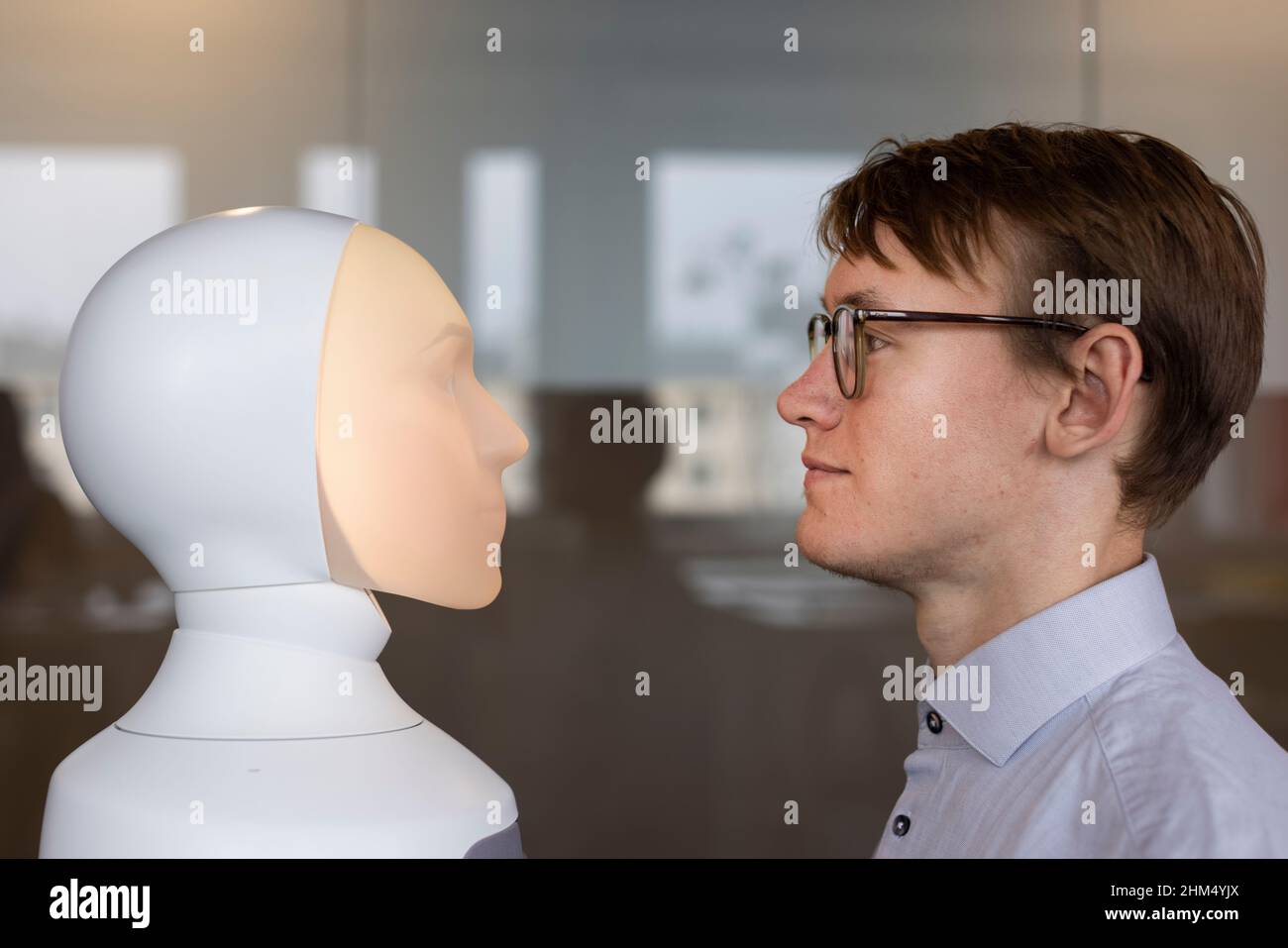 Giovane uomo che guarda l'assistente vocale del robot Foto Stock