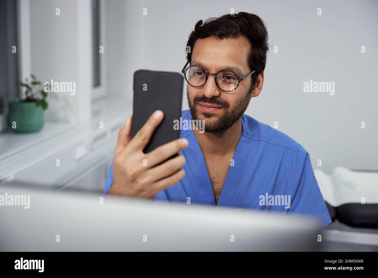 Medico di sesso maschile che ha una consultazione online su smartphone Foto Stock