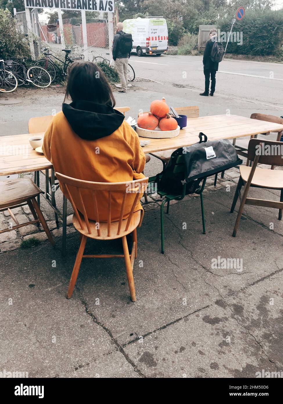 Donna seduta fuori ad un tavolo comune con un maglione giallo senape Foto  stock - Alamy