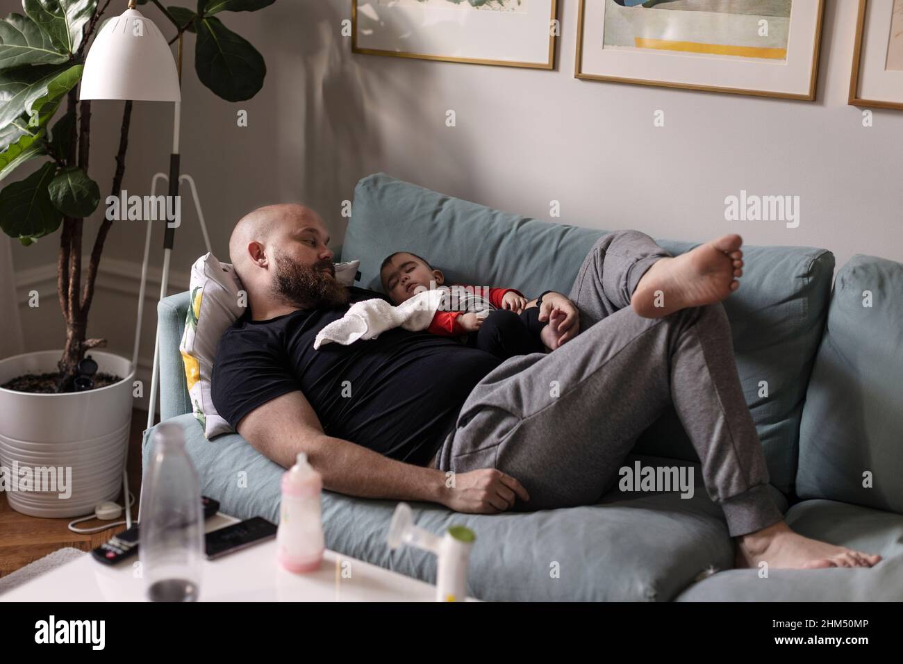 Padre che si rilassa con il bambino sul divano Foto Stock