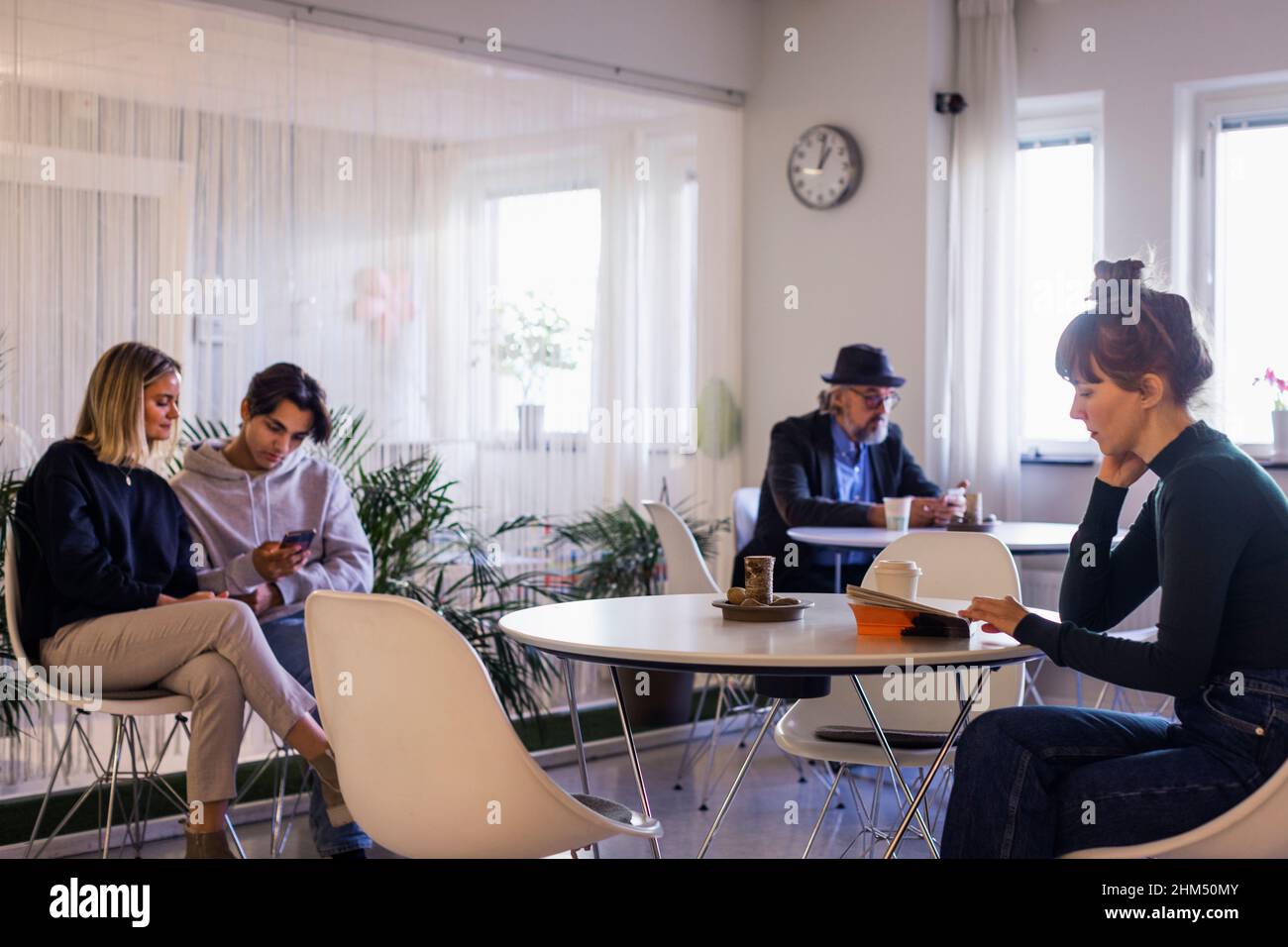 Persone sedute ai tavoli in sala d'attesa Foto Stock