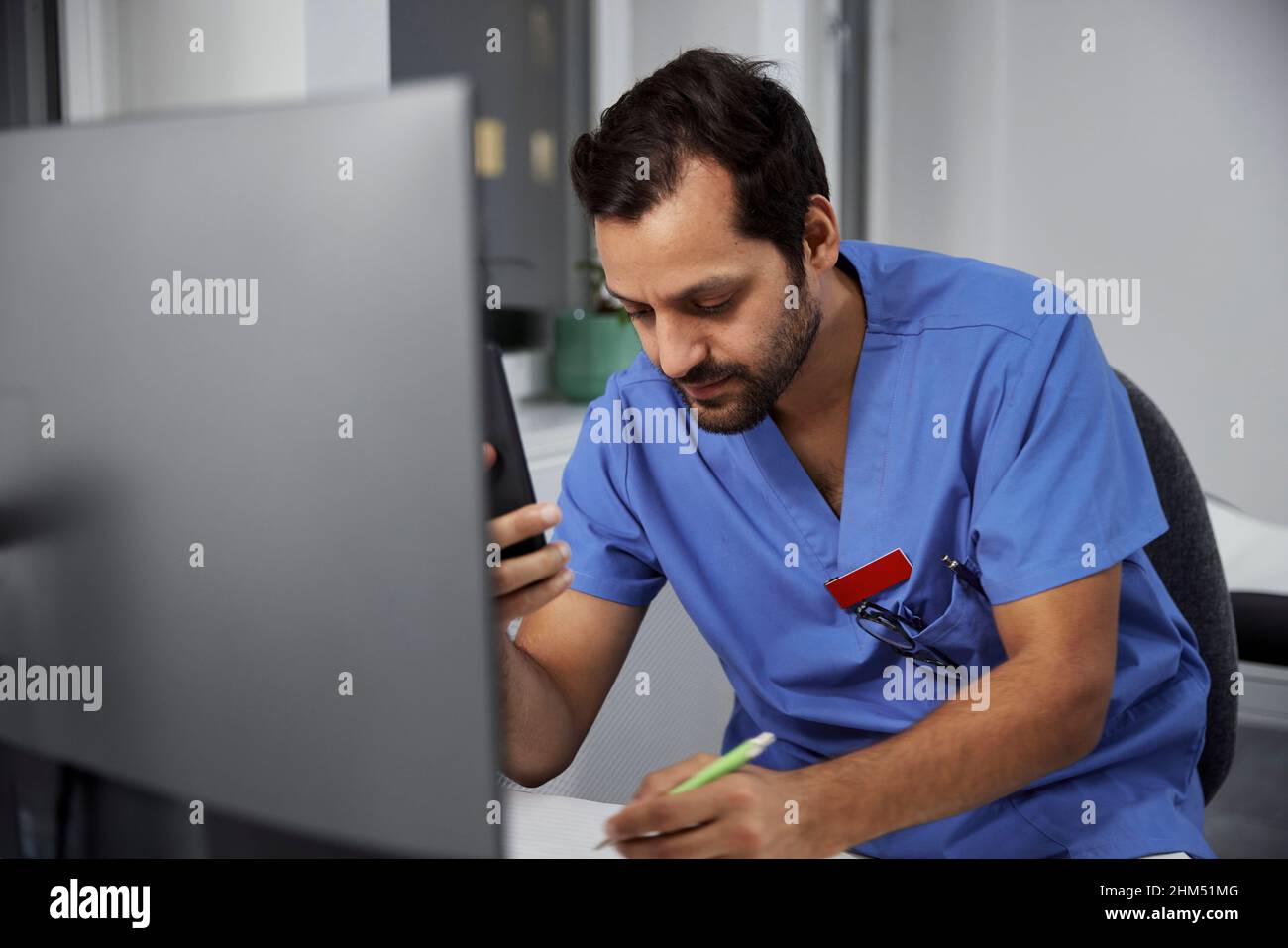 Medico di sesso maschile che usa lo smartphone in ufficio Foto Stock
