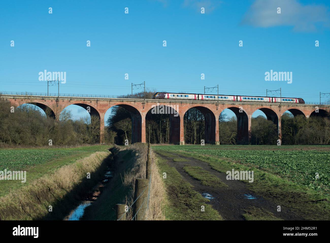 Treno passeggeri che attraversa viadotto ferroviario sopra i terreni agricoli nella contea di Durham Foto Stock