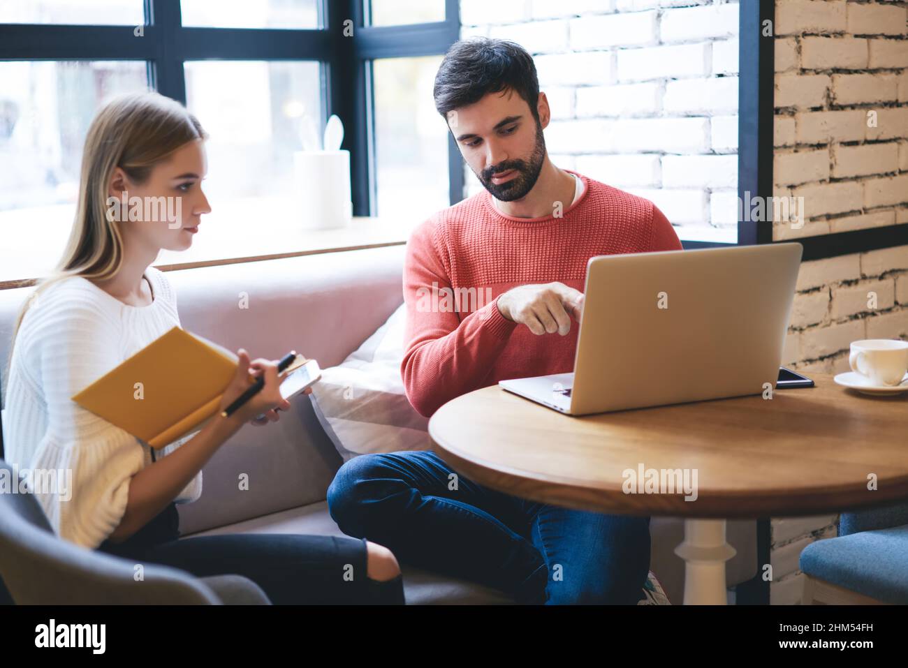 Uomo e donna concentrati a guardare le notizie sul laptop in un caffè Foto Stock