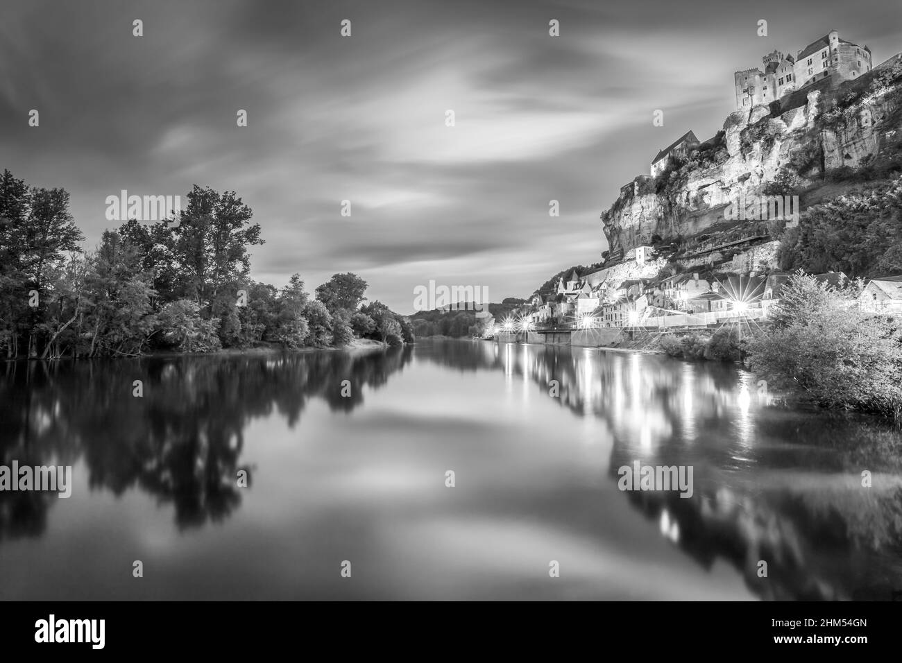 Nero e bianco di Chateau Beynac lungo dopo il tramonto con il fiume Dordogna e le luci del villaggio che riflettono nell'acqua Beynac Dordogna Francia Foto Stock