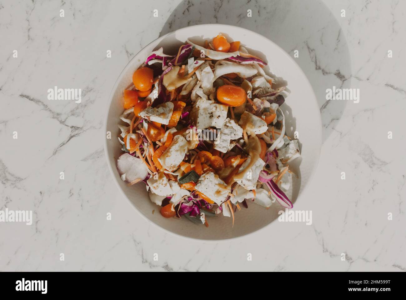 Insalata di tofu con tomatos gialli e rossi e noodle in ciotola bianca Foto Stock