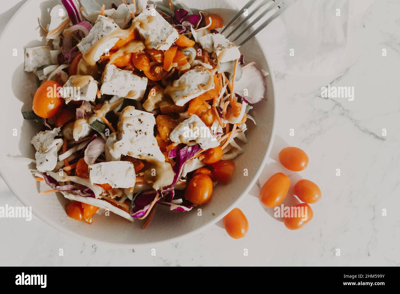 Insalata di tofu con tomatos gialli e rossi e noodle in ciotola bianca Foto Stock