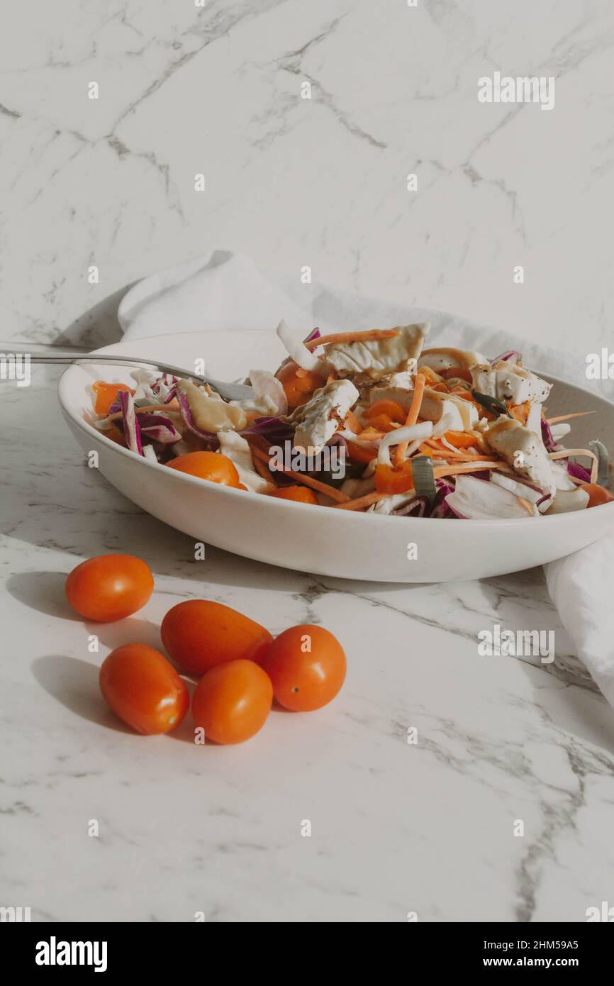 Insalata di tofu con tomatos gialli e rossi e noodle in ciotola bianca Foto Stock