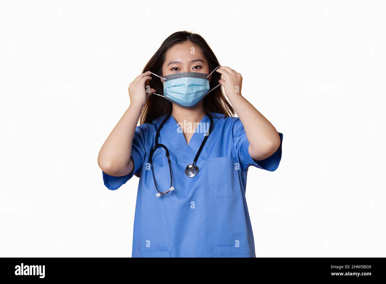 Foto studio con sfondo bianco di un medico asiatico che mette una maschera igienica sul suo viso Foto Stock