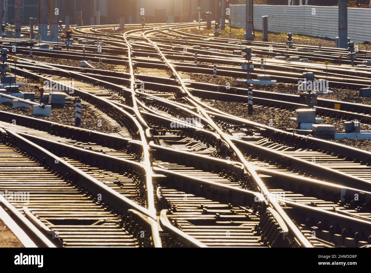 La strada ferroviaria illuminata dal sole, le rotaie e l'attraversamento delle frecce ferroviarie riflettono una luce brillante Foto Stock