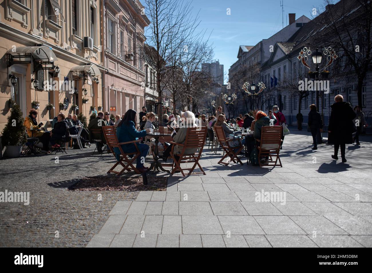 Belgrado, Serbia, 6 feb 2022: Vista di un caffè affollato di strada a Zemun con gli ospiti seduti che catturano un po' di sole invernale Foto Stock