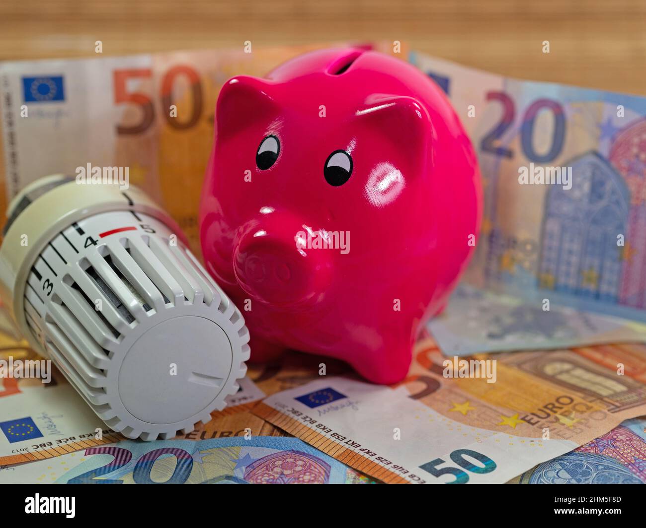 Termostato e banco di porcellini simbolico per i costi di riscaldamento Foto Stock