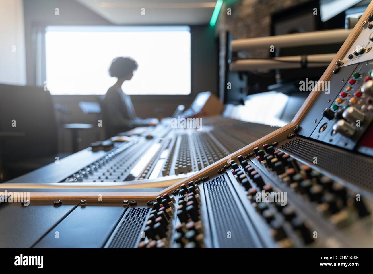Pannello di controllo di uno studio di registrazione musicale con una donna sullo sfondo Foto Stock