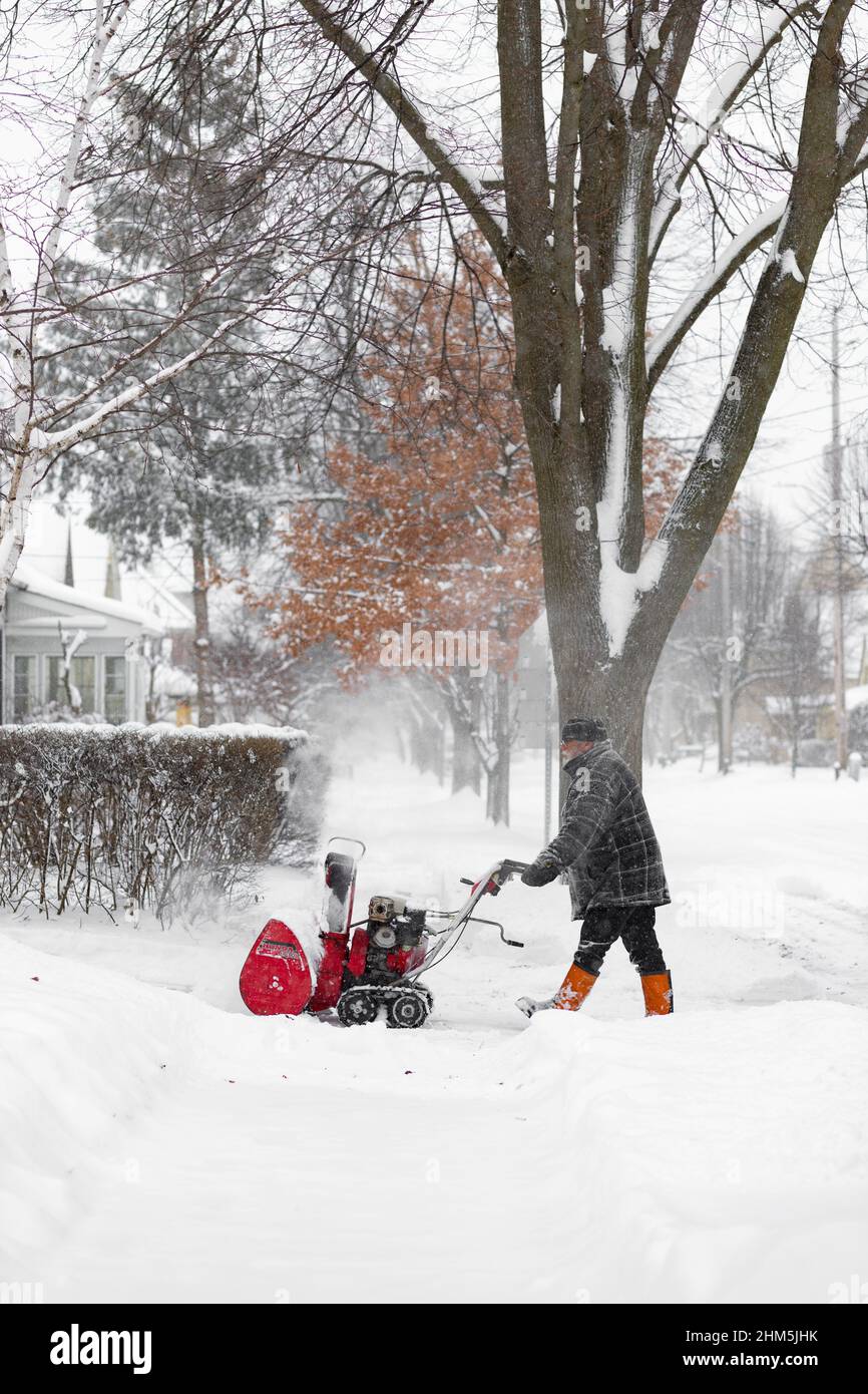 Uomo che pulisce un vialetto coperto di neve con un spazzaneve. Londra, Ontario. Canada Foto Stock