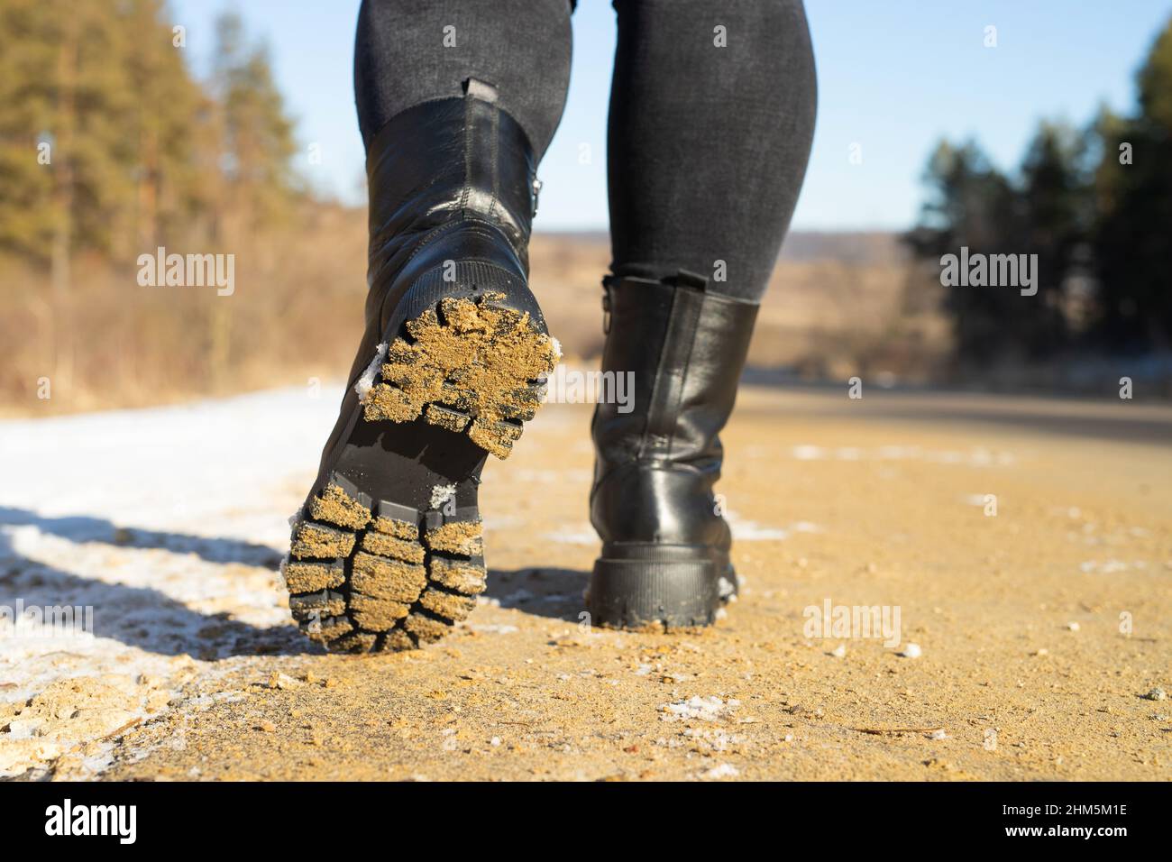 Back view photo of donna piedi indossare scarpe invernali camminare sulla strada, viaggiatore nel fine settimana giorno di sole. Foto Stock