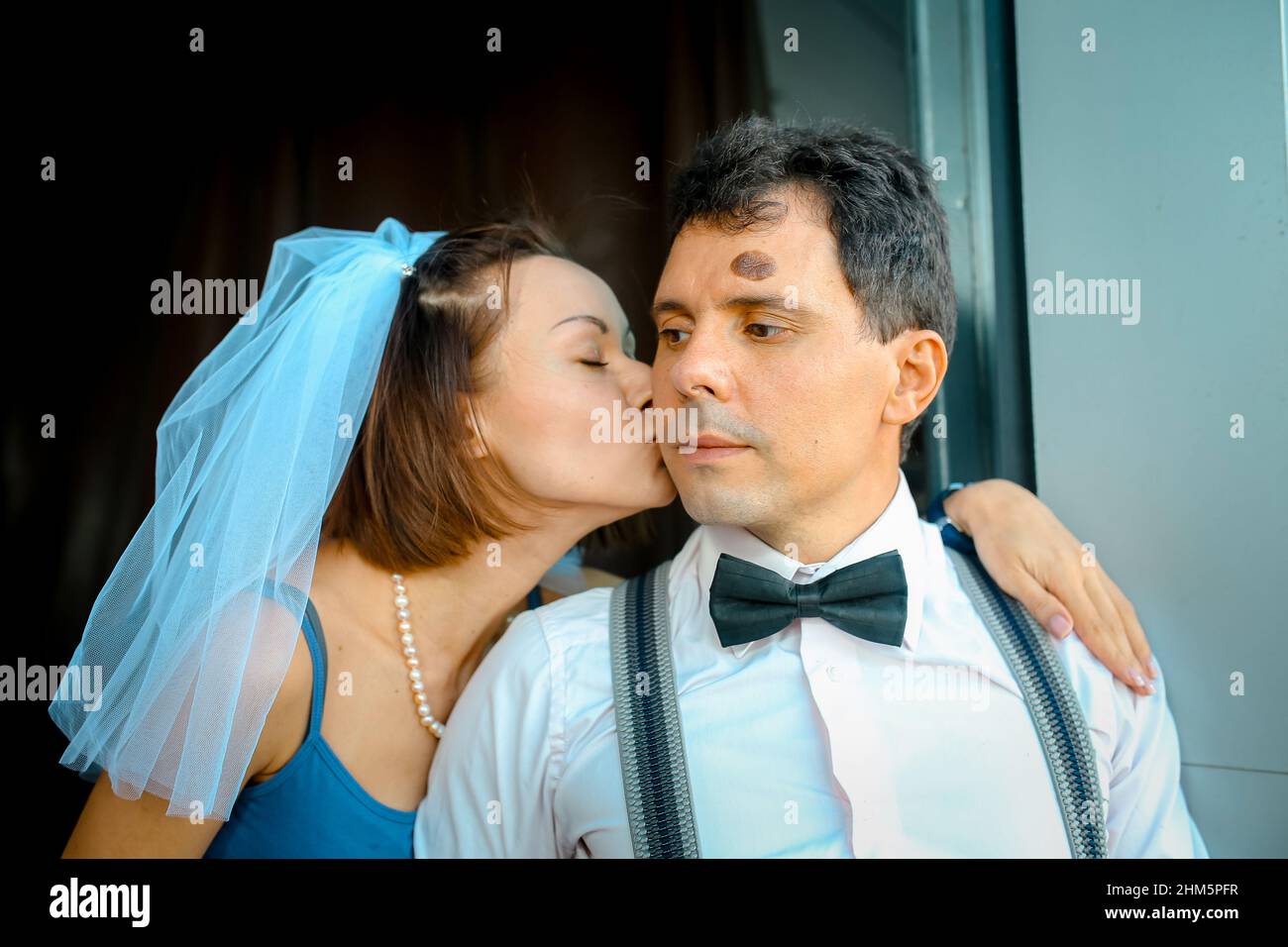 Ritratto di una giovane coppia in abito da sposa che celebra il loro anniversario di matrimonio. Sorridi, bacia, tenendo insieme il bouquet, amore. Foto Stock