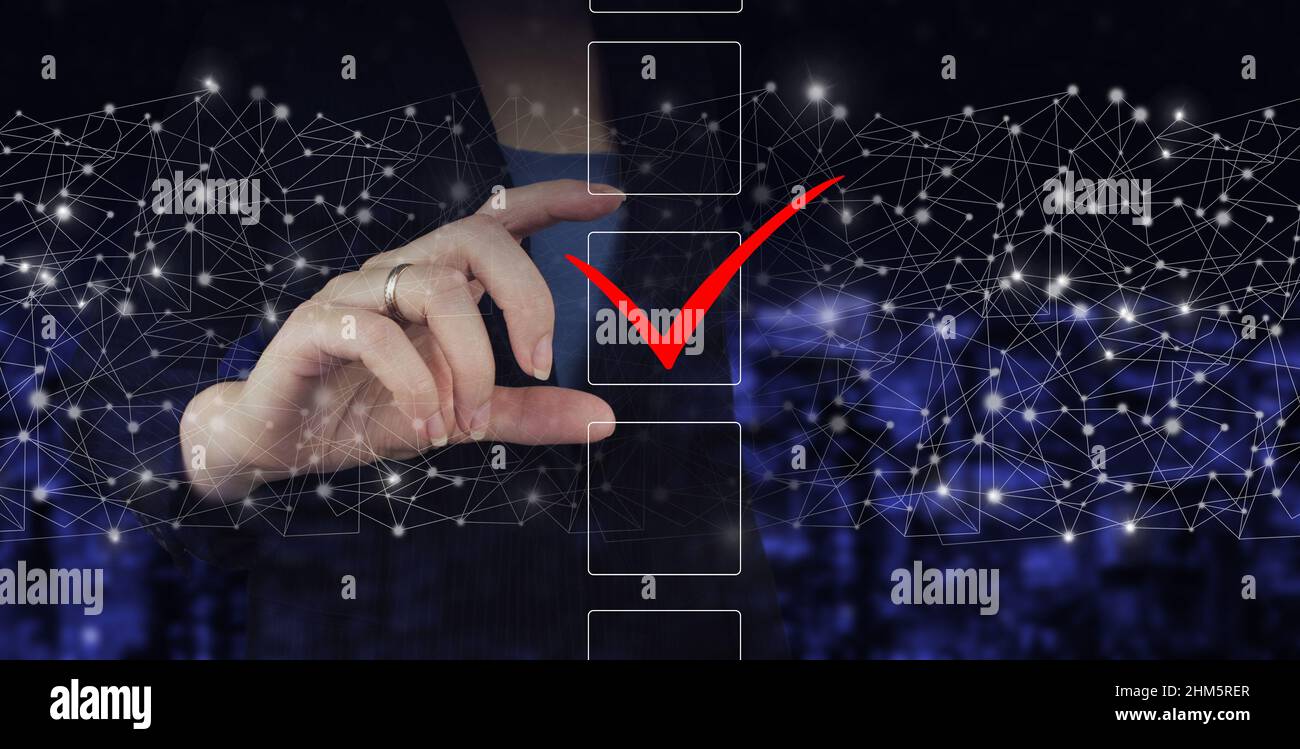 Icona di segno di spunta, referendum, forum, concetto di lista di controllo, segno di spunta, processo decisionale. Mano tenere segno ologramma digitale sulla città sfondo sfocato scuro Foto Stock