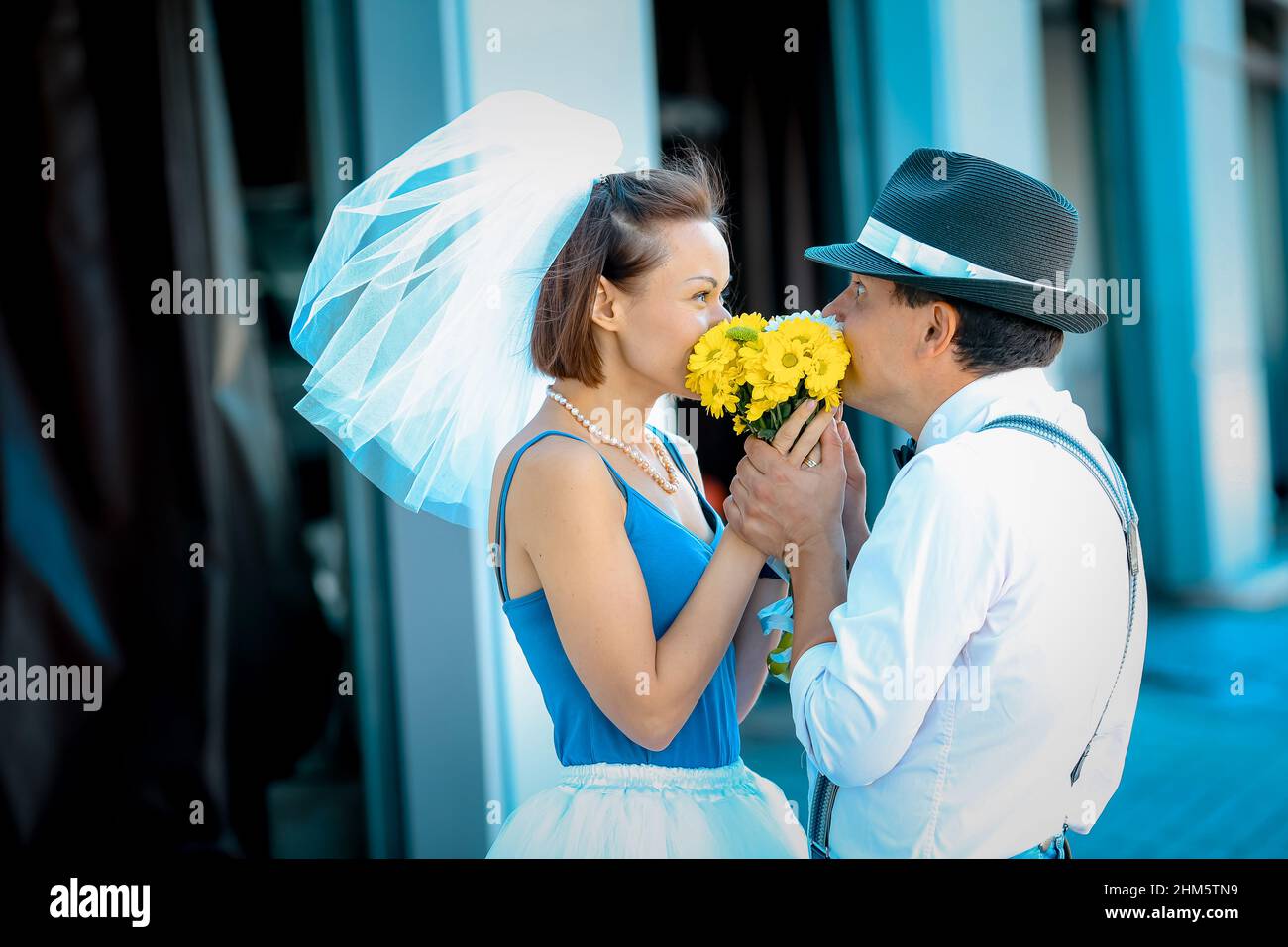 Ritratto di una giovane coppia in abito da sposa che celebra il loro anniversario di matrimonio. Sorridi, bacia, tenendo insieme il bouquet, amore. Foto Stock