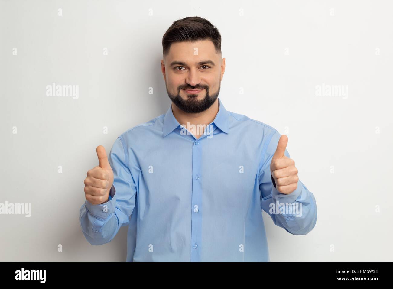 Ritratto di un uomo d'affari felice in una camicia che tiene i pollici in su. Foto Stock