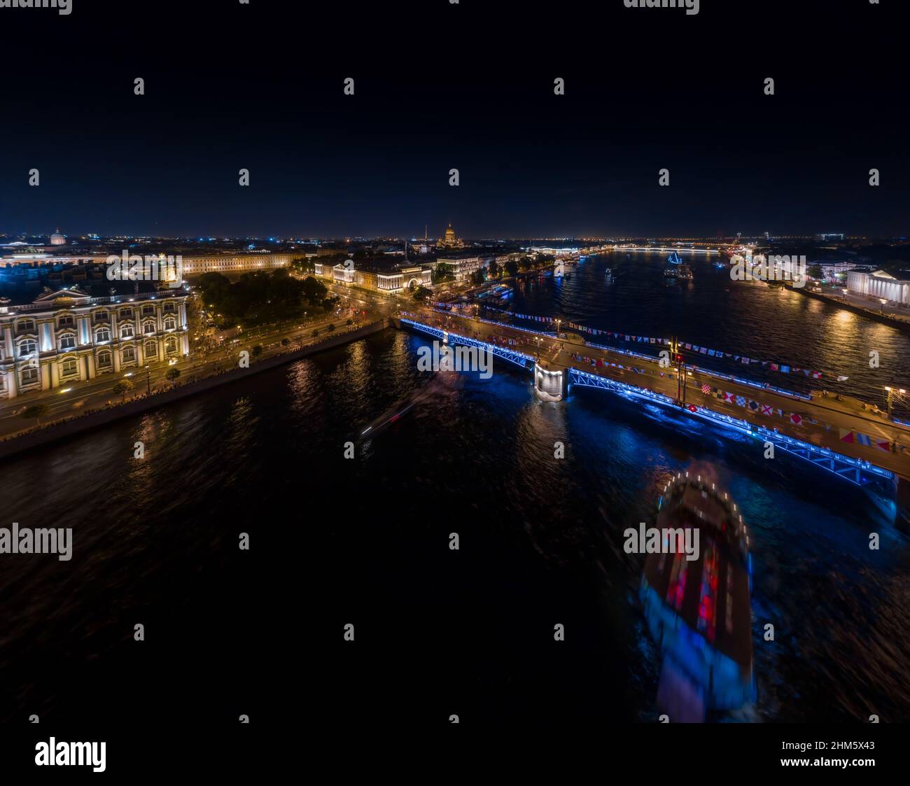 Paesaggio notturno di festeggiamenti il giorno della Marina russa, illuminazione notturna pittoresca di edifici, navi da guerra e ponti levatoi, molte persone camminano Foto Stock