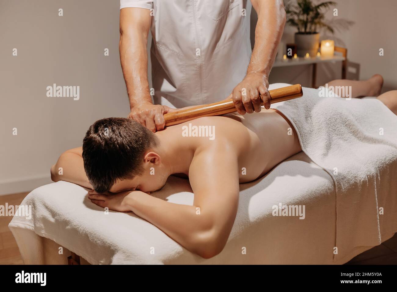 Schiena dell'uomo durante il tradizionale massaggio tailandese con bastone.  Medicina alternativa orientale con attrezzi di legno. Cura del corpo e SPA  in Tailandia resort Foto stock - Alamy