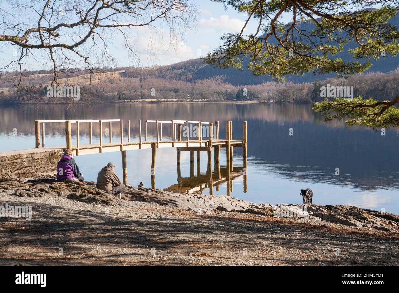 Coppia matura con cane al lago, Derwentwater, Cumbria, Inghilterra, Regno Unito Foto Stock