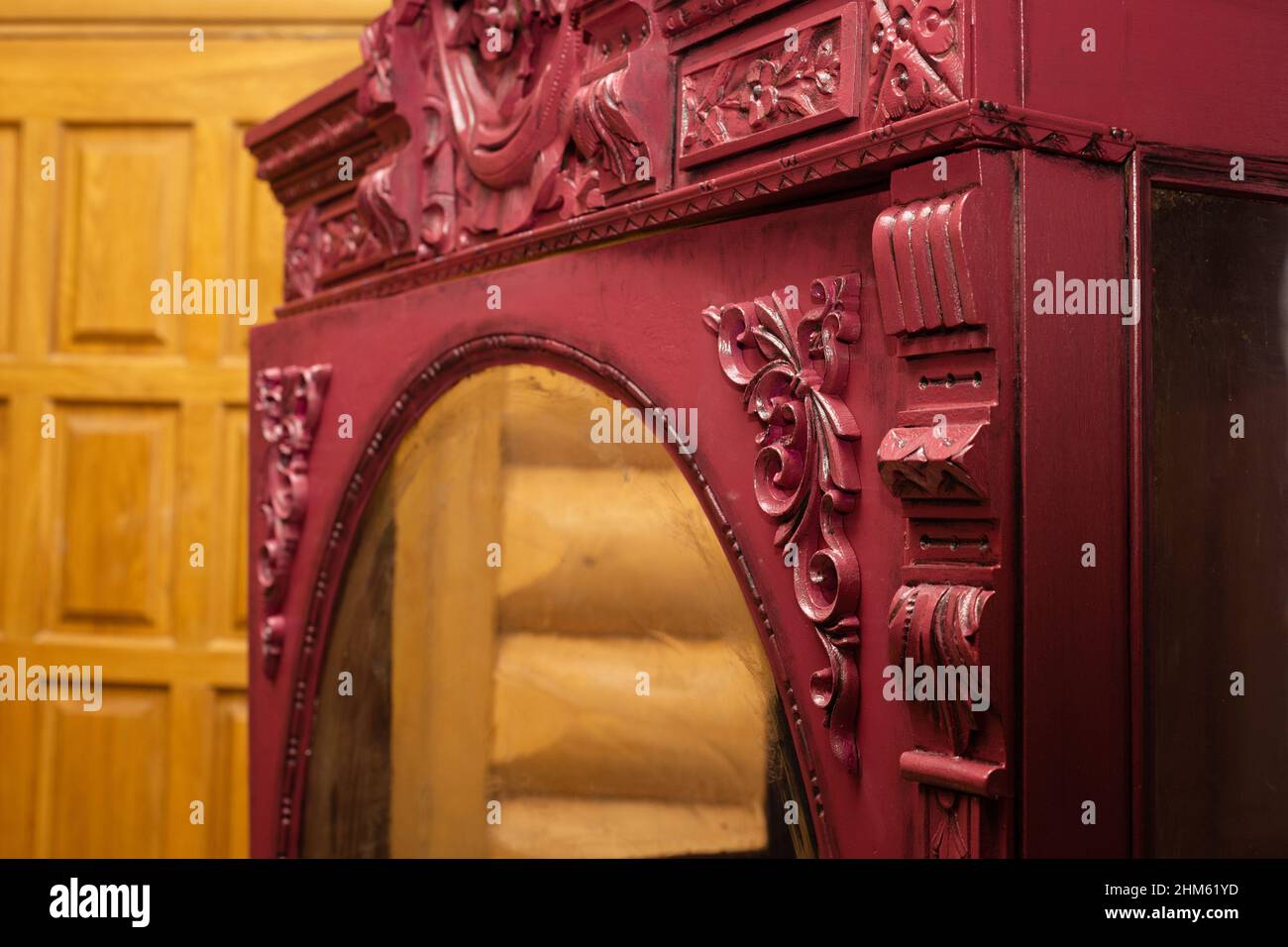 Vecchio armadio disegnato recuperato dipinto di colore rosso con vetro di fronte con pareti in legno e porta sullo sfondo. Restauro di antiquariato Foto Stock