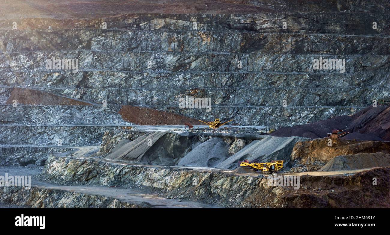 Panorama della parete a gradini della cava della diabase con due macchine di frantumazione della pietra gialla Foto Stock