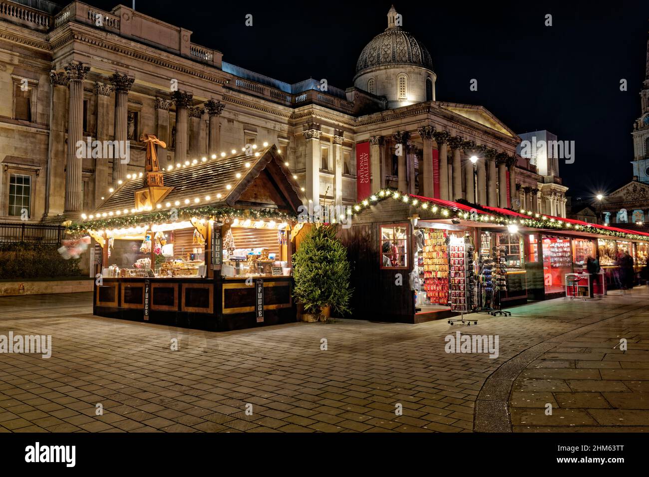 Le colorate bancarelle del Mercatino di Natale fuori dalla National Gallery a Trafalgar Square a Londra sembrano fantastiche di notte Foto Stock