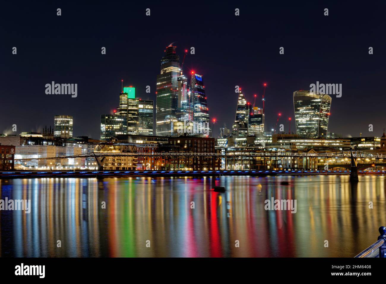 Riflessi colorati nel Tamigi dalle luci del Centro finanziario di Londra con la sua varietà di grattacieli che illuminano la notte Foto Stock