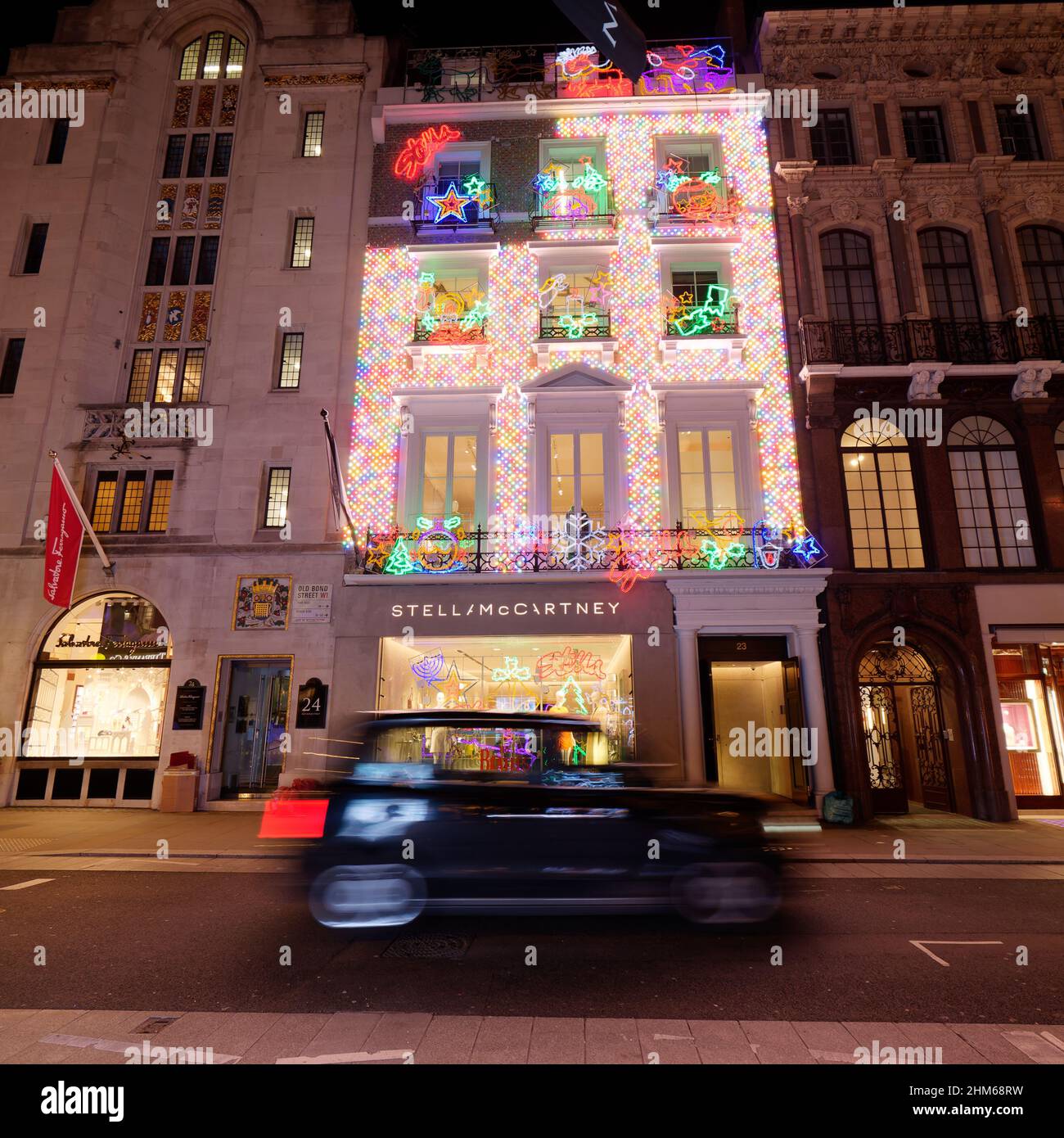 Stella McCartney negozio di moda sulla Old Bond Street come la mostra di luci di Natale si riflette in un taxi di passaggio. Londra. Foto Stock