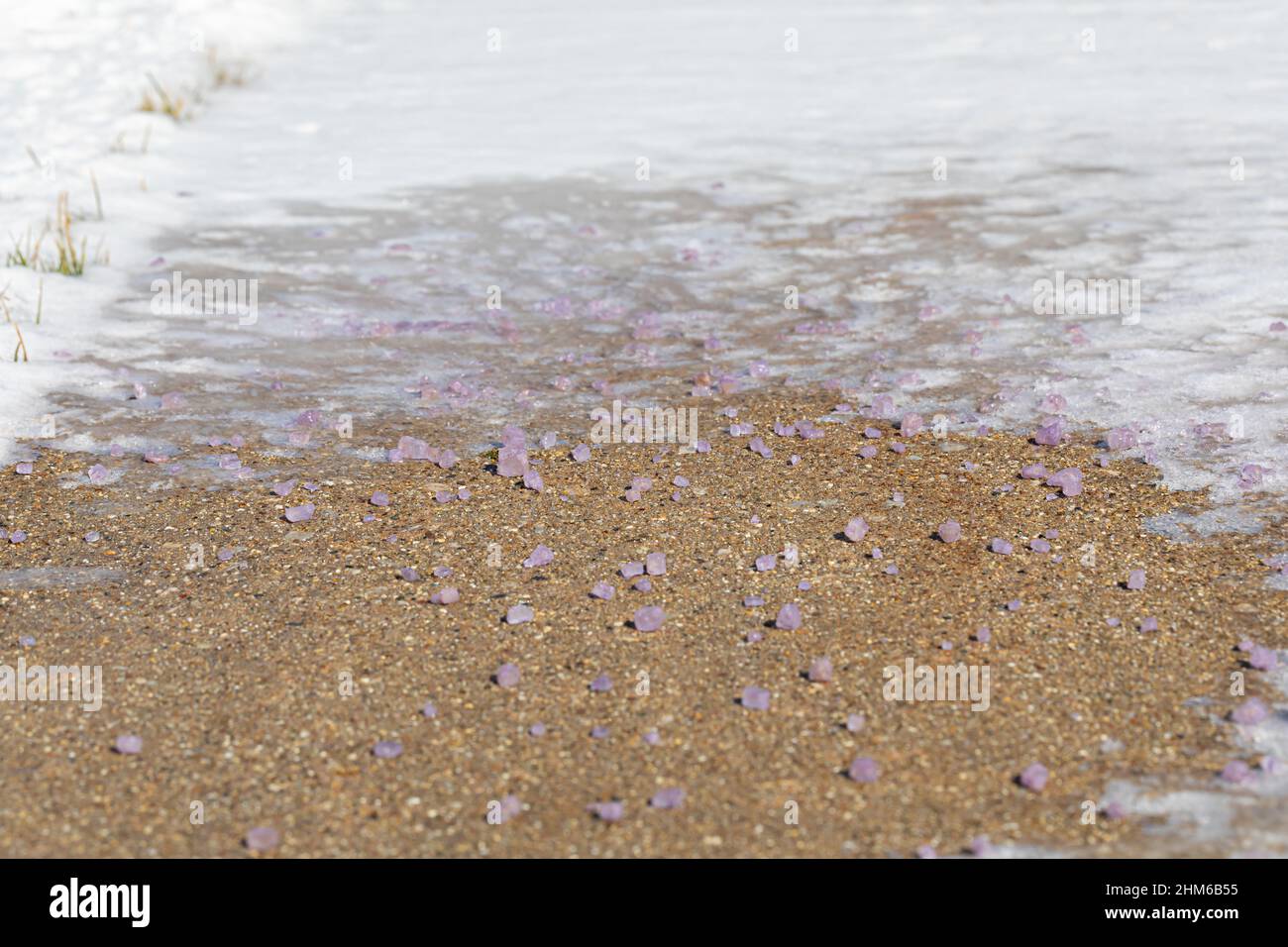Ghiaccio sciogliere il sale sciogliendo il ghiaccio e la neve sul marciapiede. Rimozione della neve, fusione del ghiaccio e sicurezza invernale Foto Stock