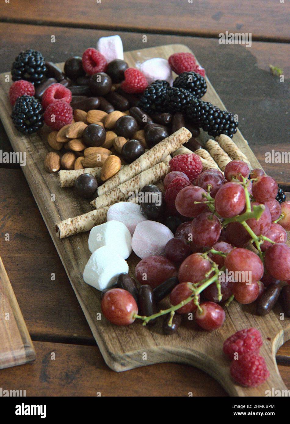 Vassoio di legno con frutti di bosco e dolci Foto Stock