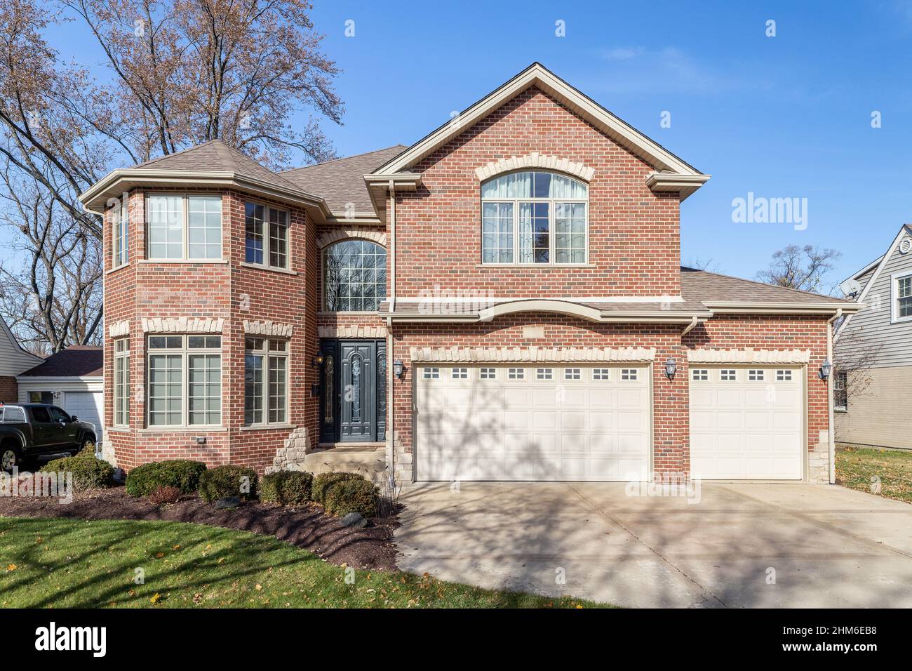 Una grande casa di mattoni rossi a due piani con un garage per tre auto. Foto Stock