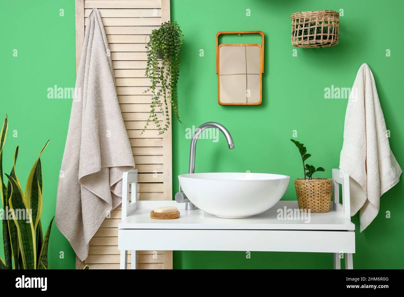 Tavolo con lavello bianco, piante domestiche e sapone vicino parete verde  in bagno Foto stock - Alamy