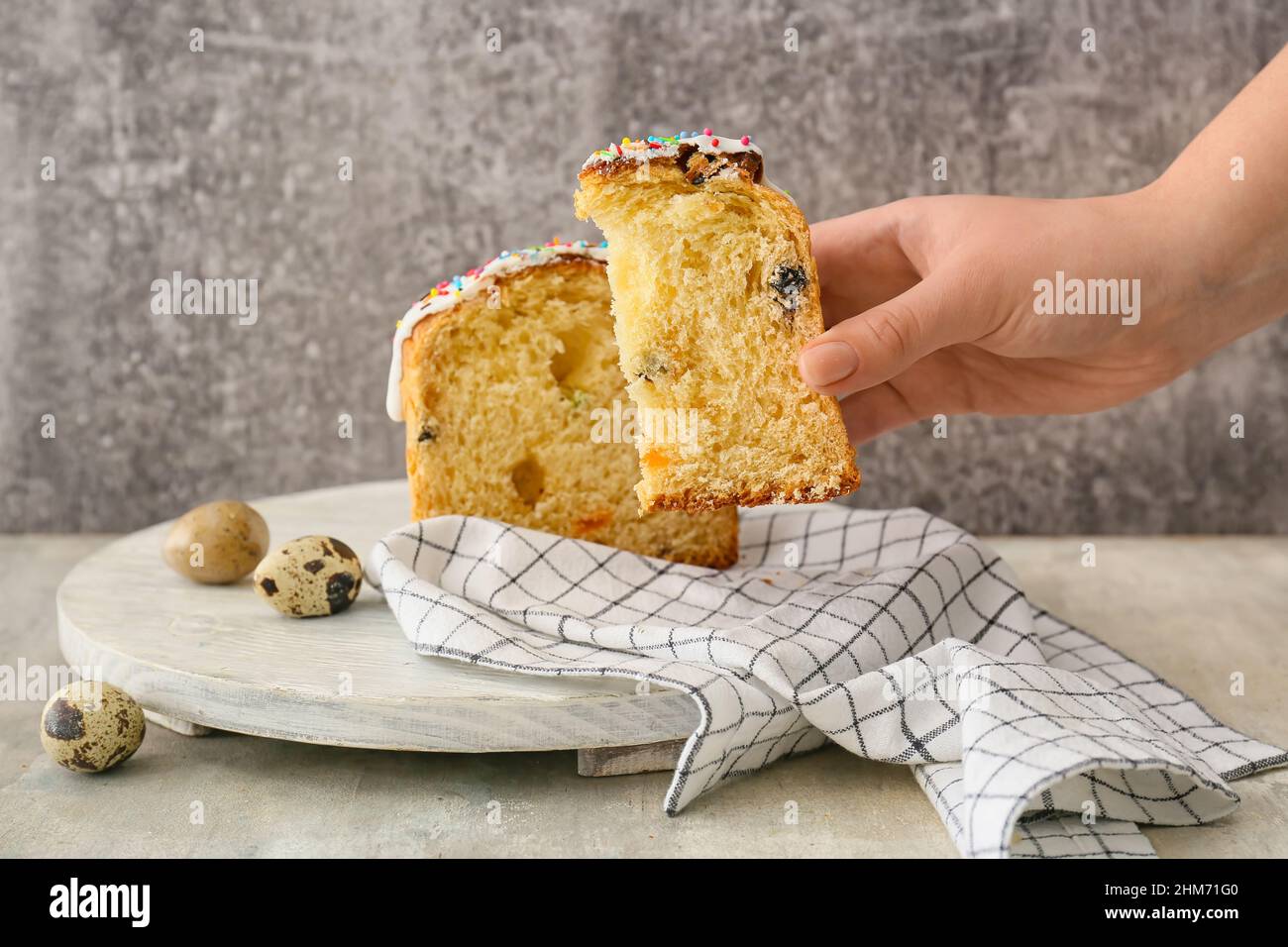 Donna che tiene un pezzo di dolce pasquale delizioso su sfondo grigio Foto Stock